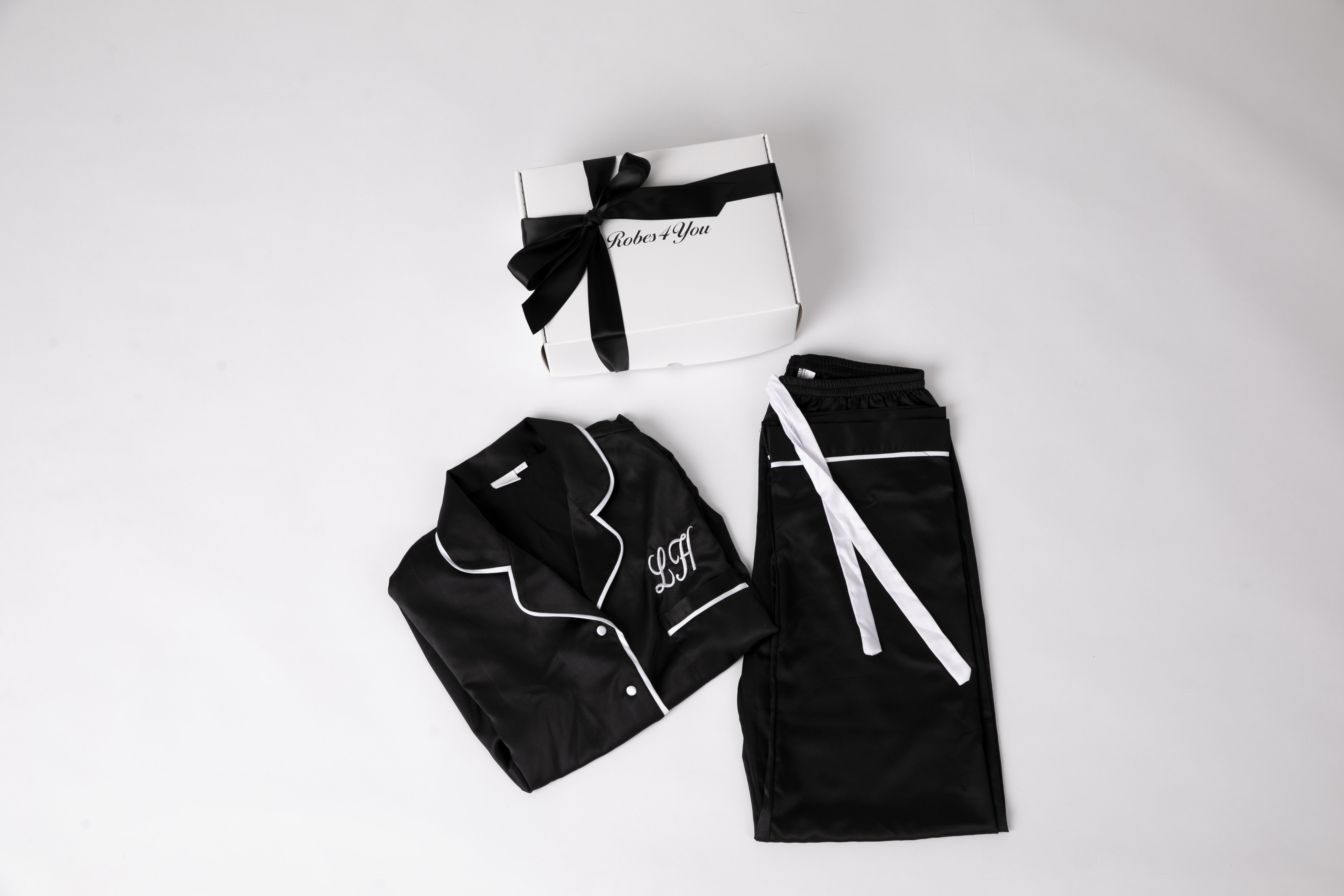 Personalised Black Satin Pjs with white Piping and snippet of champagne, candle and chocolates  presented in a gift box with bow