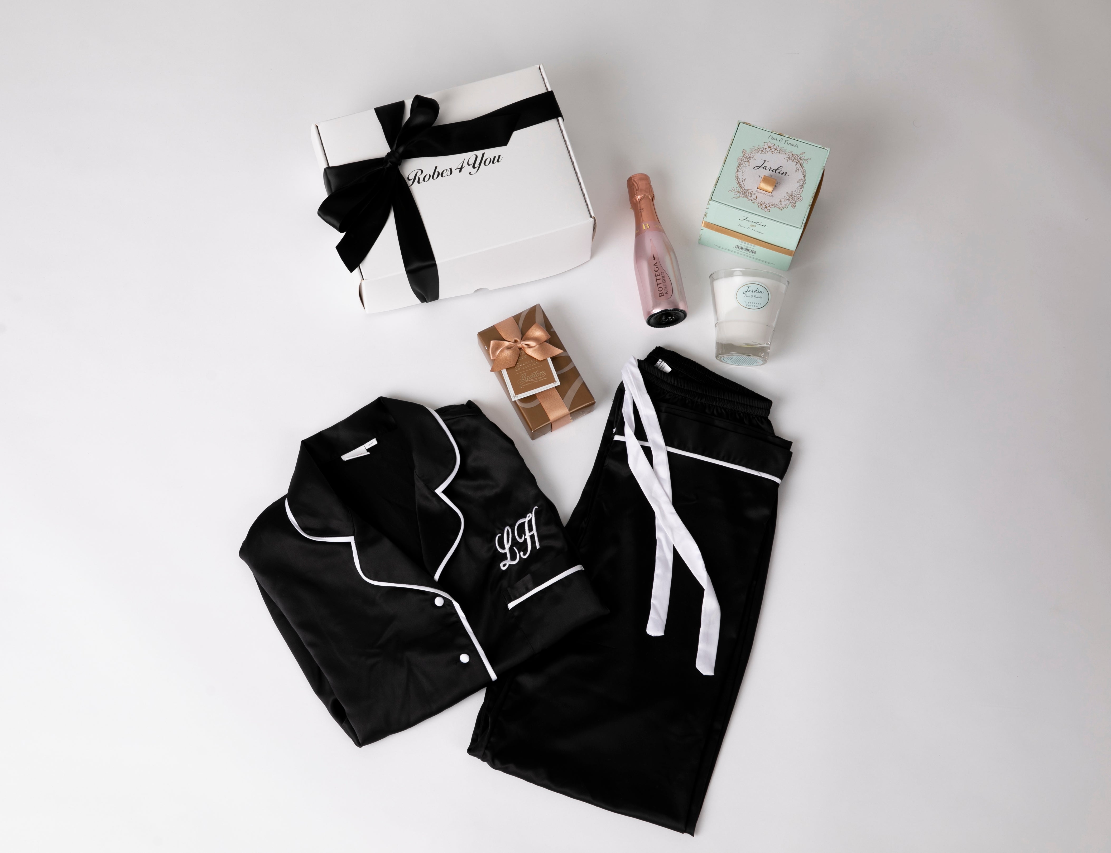 Personalised Black Satin Pjs with white Piping and snippet of champagne, candle and chocolates  presented in a gift box with bow
